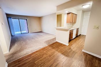 An empty living room and kitchen with a sliding glass door